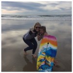 Bailey and Ellie holding a skating board at the beach