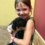 Ellie sitting and holding her poodle dog